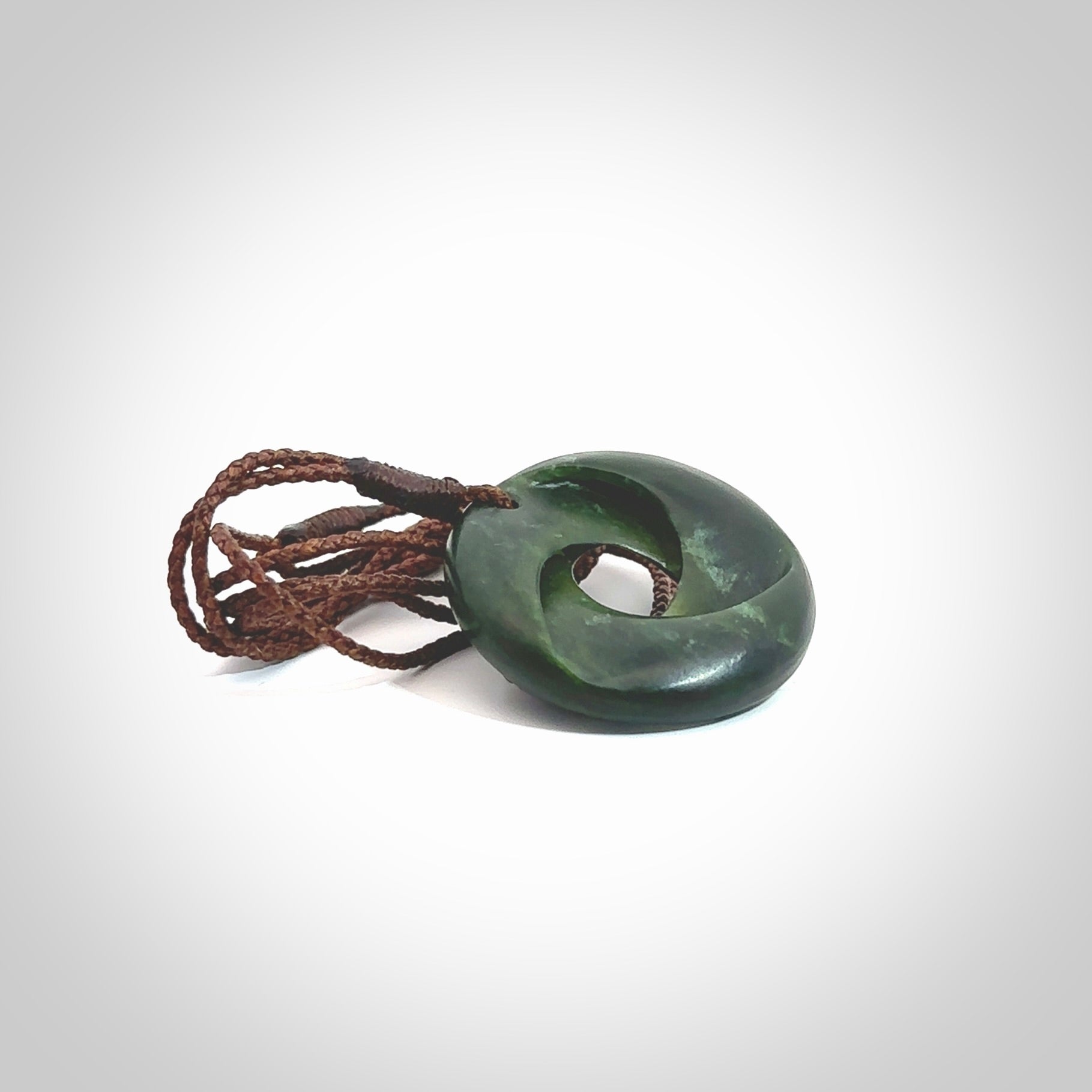 This little piece is a hand carved möbius ribbon pendant. We've carved this from New Zealand Jade. It has very subtle colour variations in the stone and is a delightful, small and artistic piece of jewellery. Hand made by Kyohei Noguchi and delivered to you in a kete pouch. Delivered to you on an adjustable brown cord.