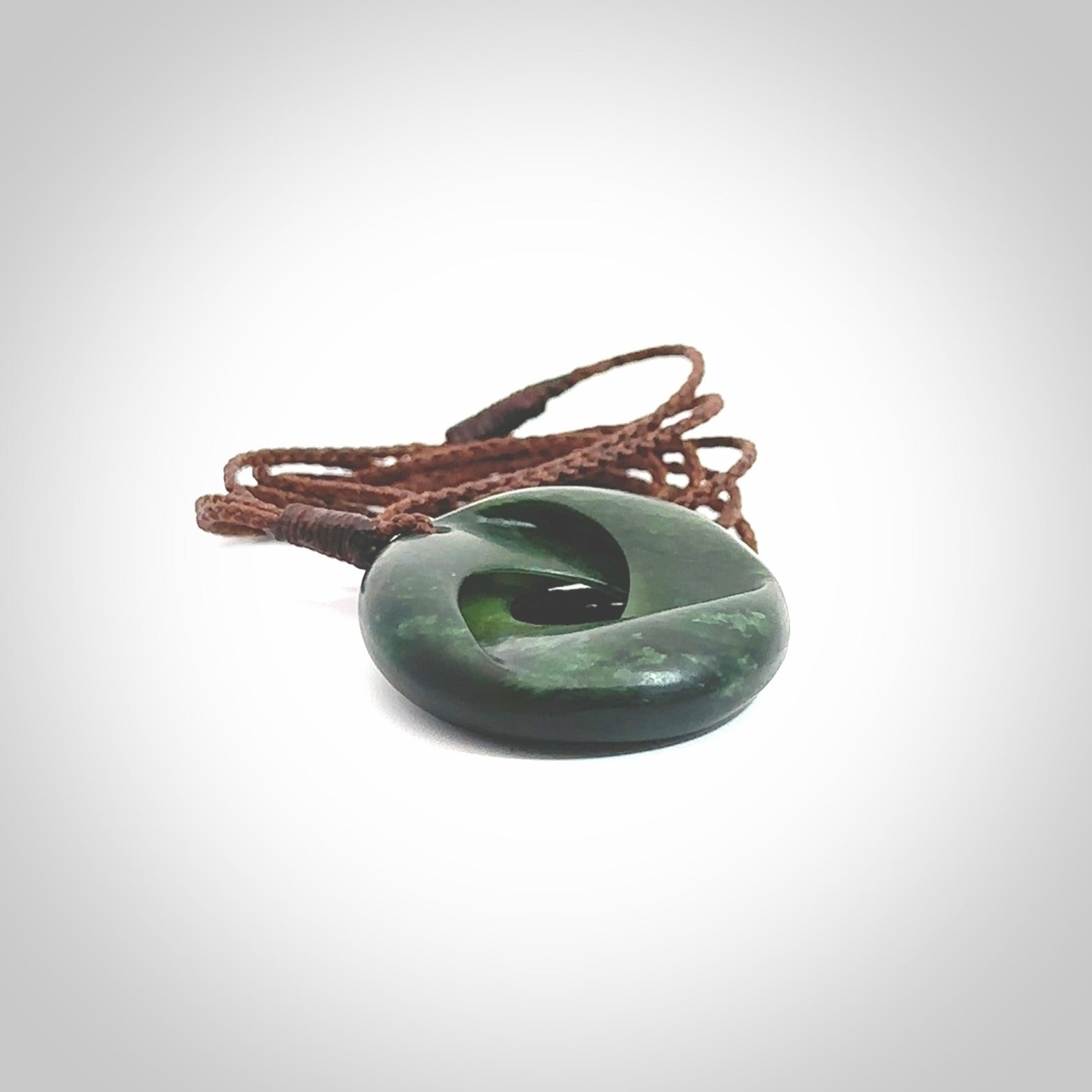 This little piece is a hand carved möbius ribbon pendant. We've carved this from New Zealand Jade. It has very subtle colour variations in the stone and is a delightful, small and artistic piece of jewellery. Hand made by Kyohei Noguchi and delivered to you in a kete pouch. Delivered to you on an adjustable brown cord.