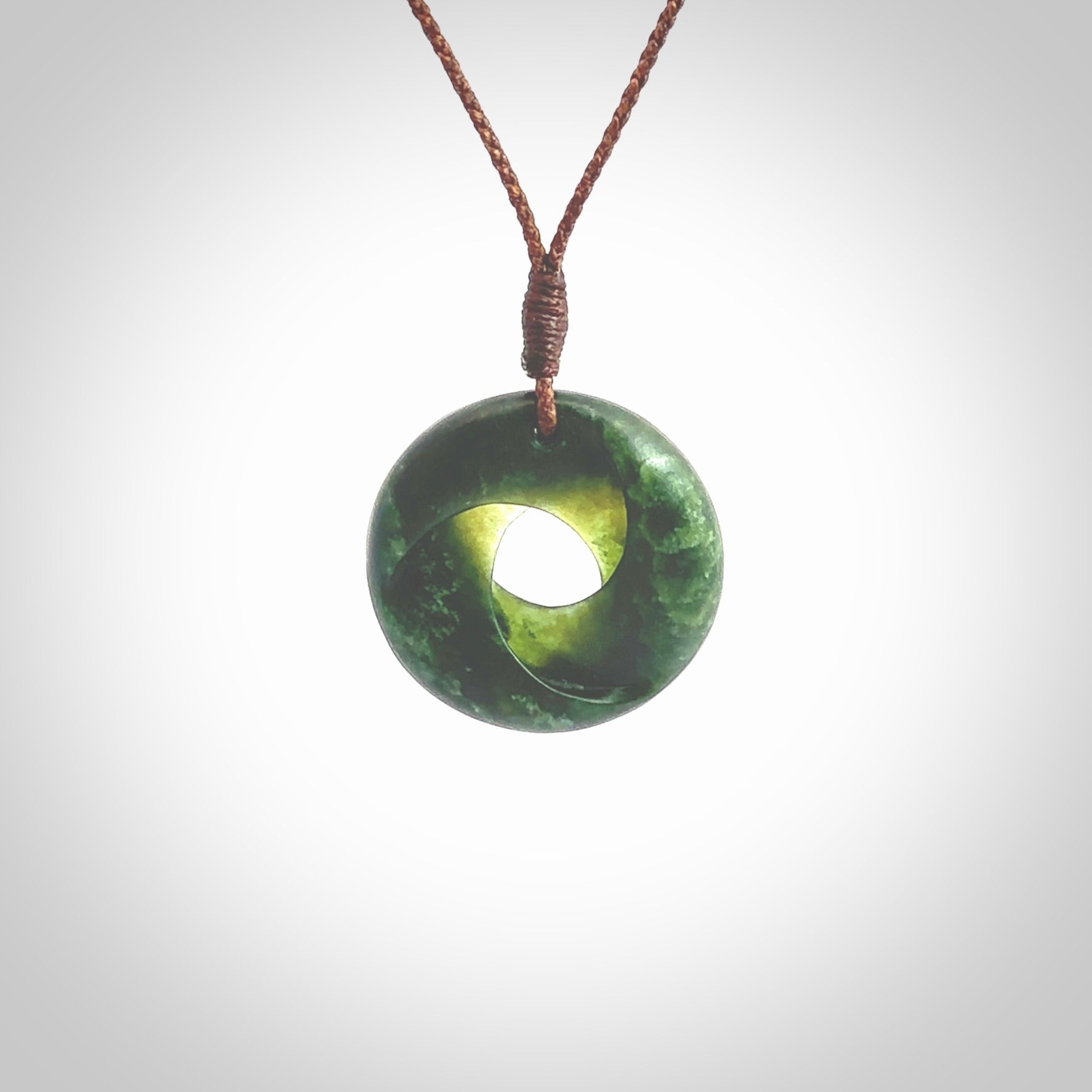 This little piece is a hand carved möbius ribbon pendant. We've carved this from New Zealand Jade. It has very subtle colour variations in the stone and is a delightful, small and artistic piece of jewellery. Hand made by Kyohei Noguchi and delivered to you in a kete pouch. Delivered to you on an adjustable brown cord.