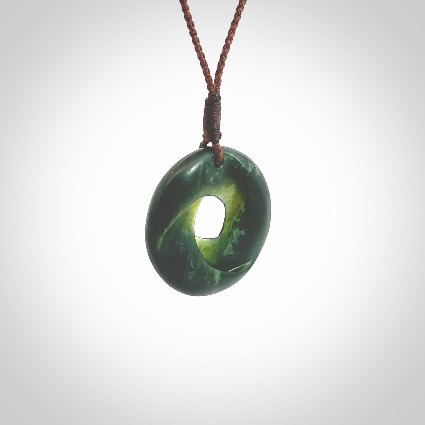 This little piece is a hand carved möbius ribbon pendant. We've carved this from New Zealand Jade. It has very subtle colour variations in the stone and is a delightful, small and artistic piece of jewellery. Hand made by Kyohei Noguchi and delivered to you in a kete pouch. Delivered to you on an adjustable brown cord.