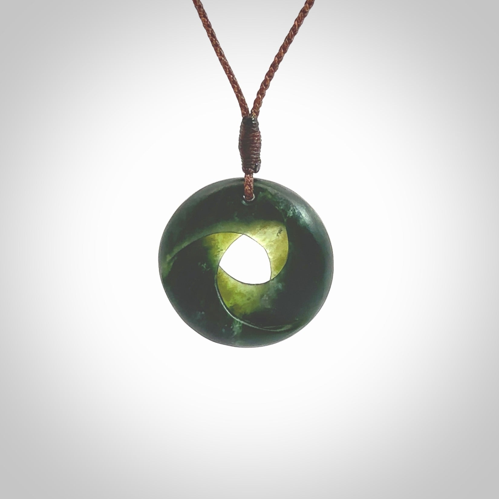 This little piece is a hand carved möbius ribbon pendant. We've carved this from New Zealand Jade. It has very subtle colour variations in the stone and is a delightful, small and artistic piece of jewellery. Hand made by Kyohei Noguchi and delivered to you in a kete pouch. Delivered to you on an adjustable brown cord.