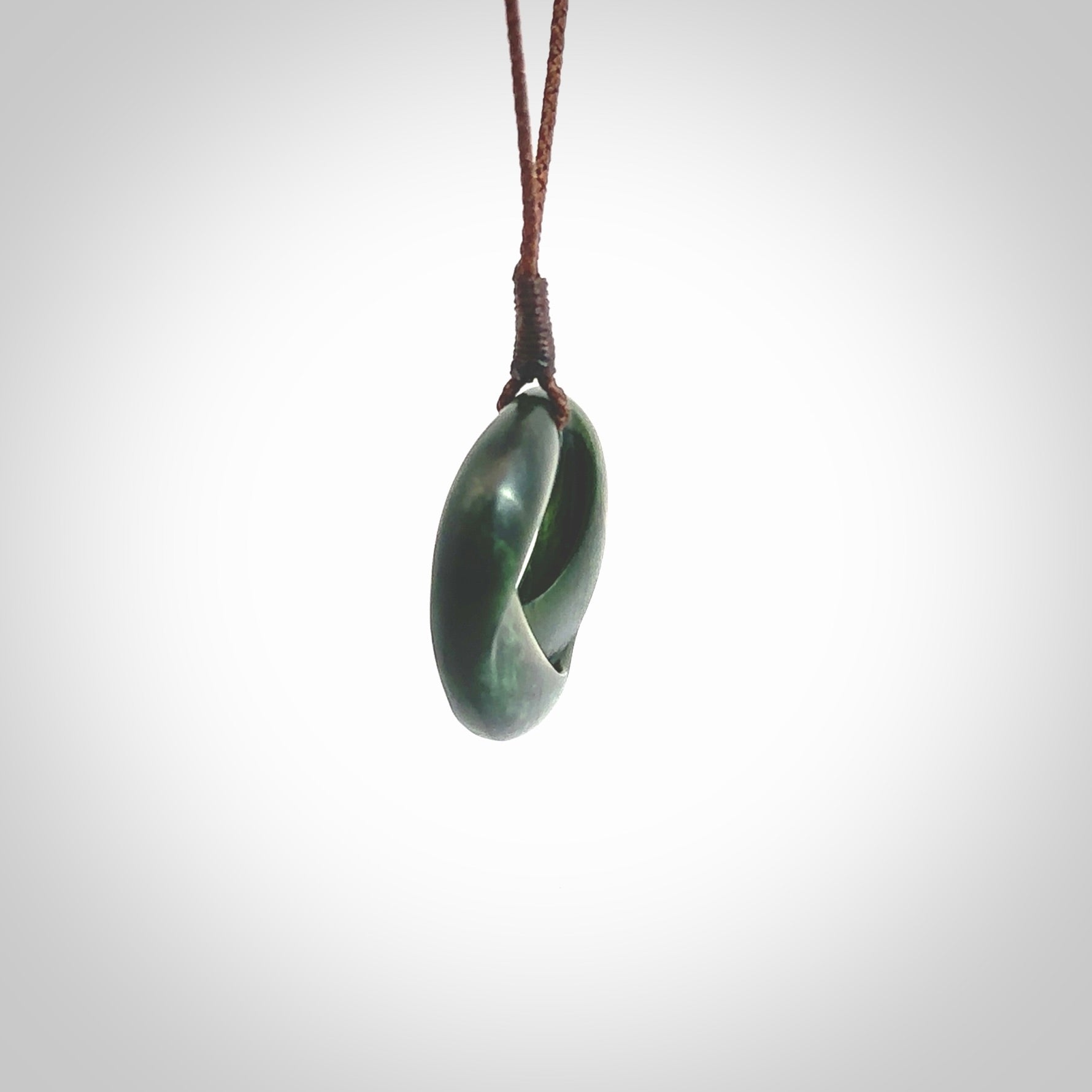 This little piece is a hand carved möbius ribbon pendant. We've carved this from New Zealand Jade. It has very subtle colour variations in the stone and is a delightful, small and artistic piece of jewellery. Hand made by Kyohei Noguchi and delivered to you in a kete pouch. Delivered to you on an adjustable brown cord.