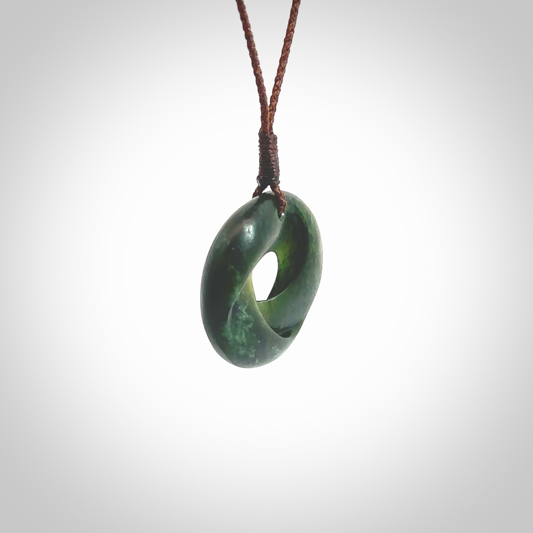 This little piece is a hand carved möbius ribbon pendant. We've carved this from New Zealand Jade. It has very subtle colour variations in the stone and is a delightful, small and artistic piece of jewellery. Hand made by Kyohei Noguchi and delivered to you in a kete pouch. Delivered to you on an adjustable brown cord.