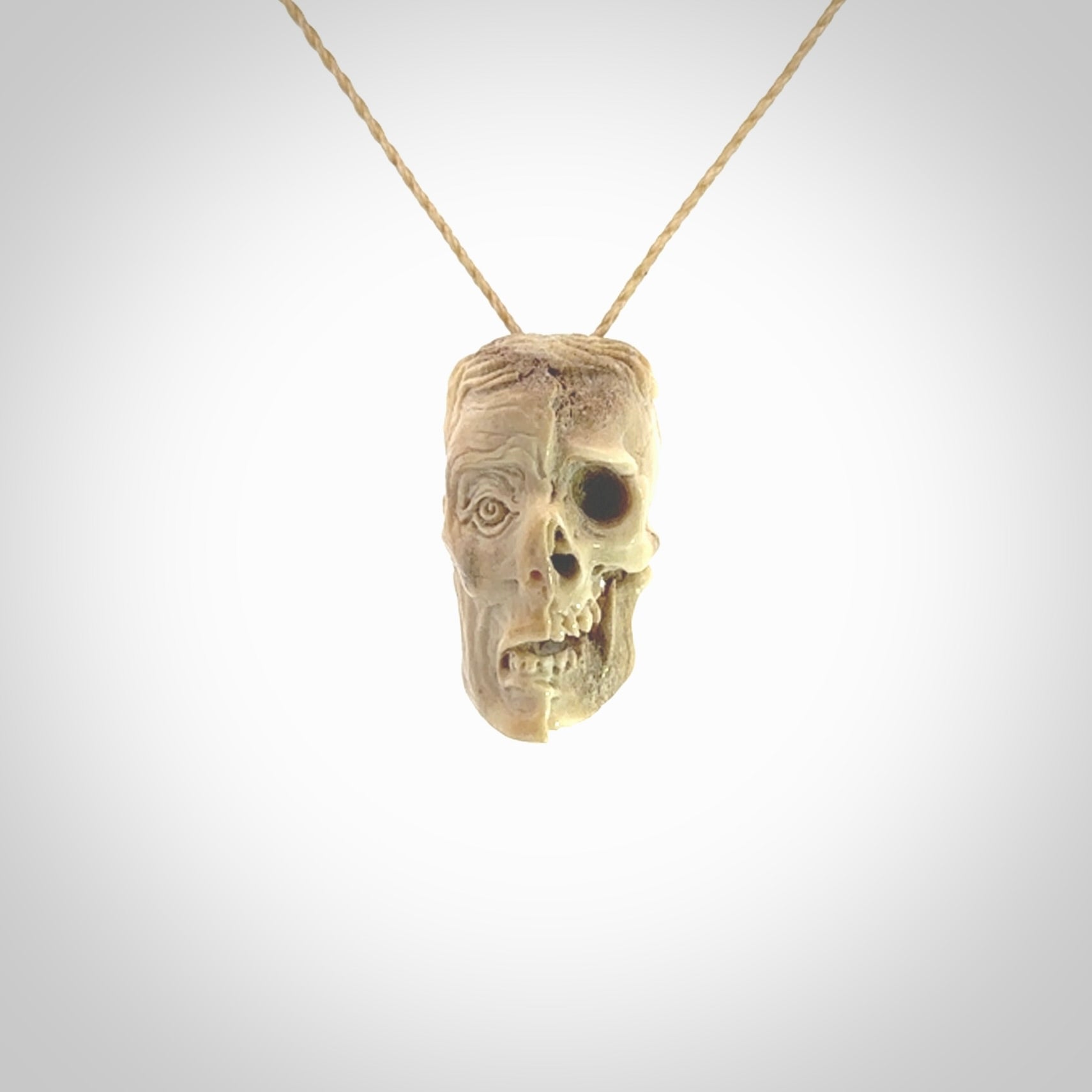 This photo shows a mummy skull pendant hand carved in deer antler. It is provided with a plaited cord necklace which is length adjustable.