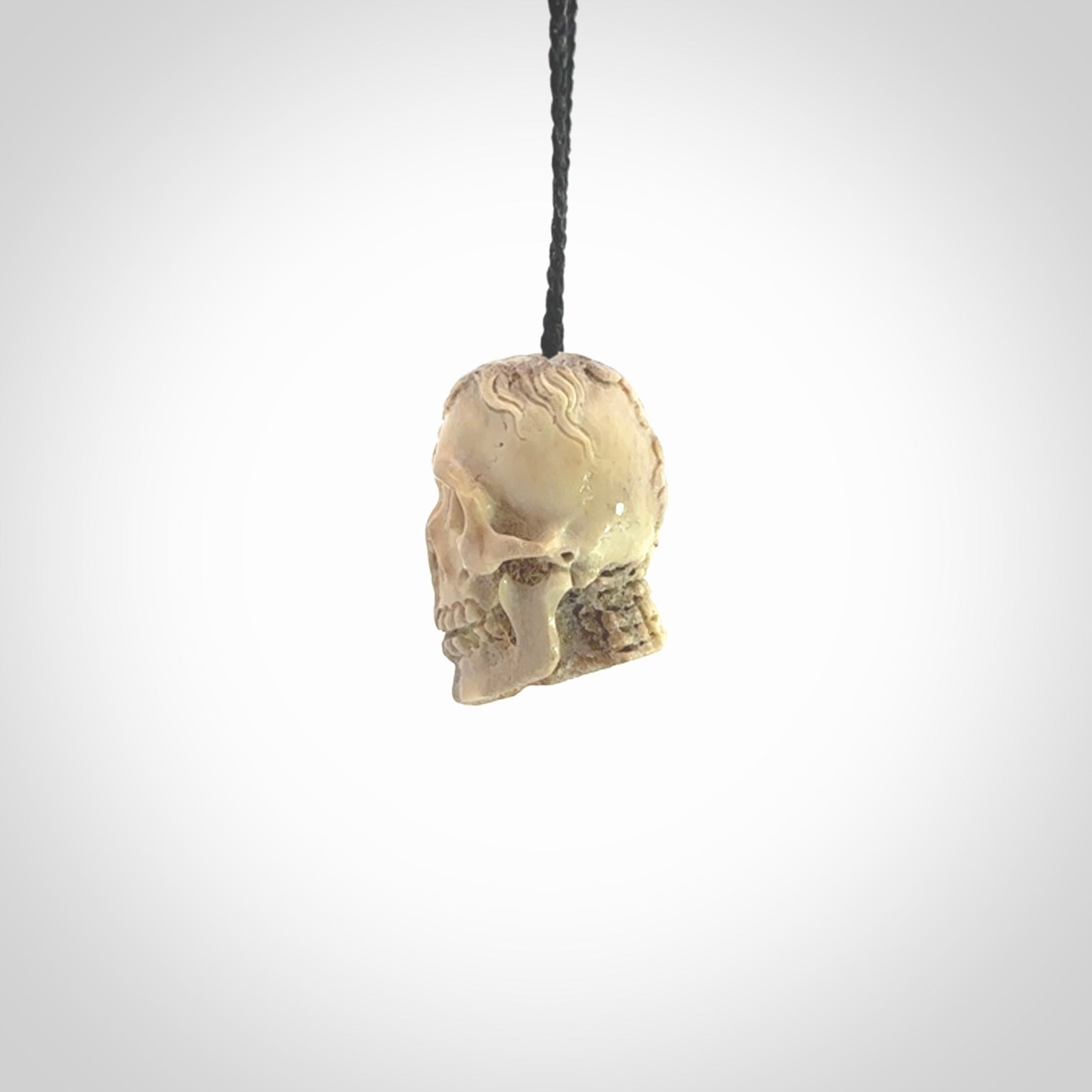 This photo shows a mummy skull pendant hand carved in deer antler. It is provided with a plaited cord necklace which is length adjustable.