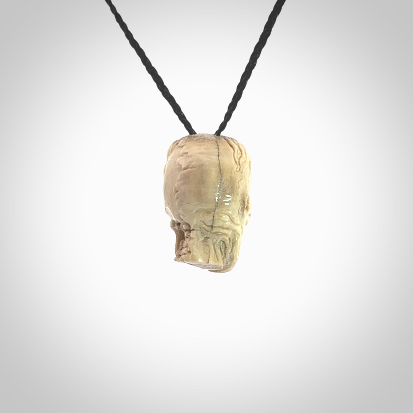 This photo shows a mummy skull pendant hand carved in deer antler. It is provided with a plaited cord necklace which is length adjustable.