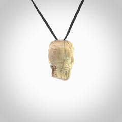 This photo shows a mummy skull pendant hand carved in deer antler. It is provided with a plaited cord necklace which is length adjustable.