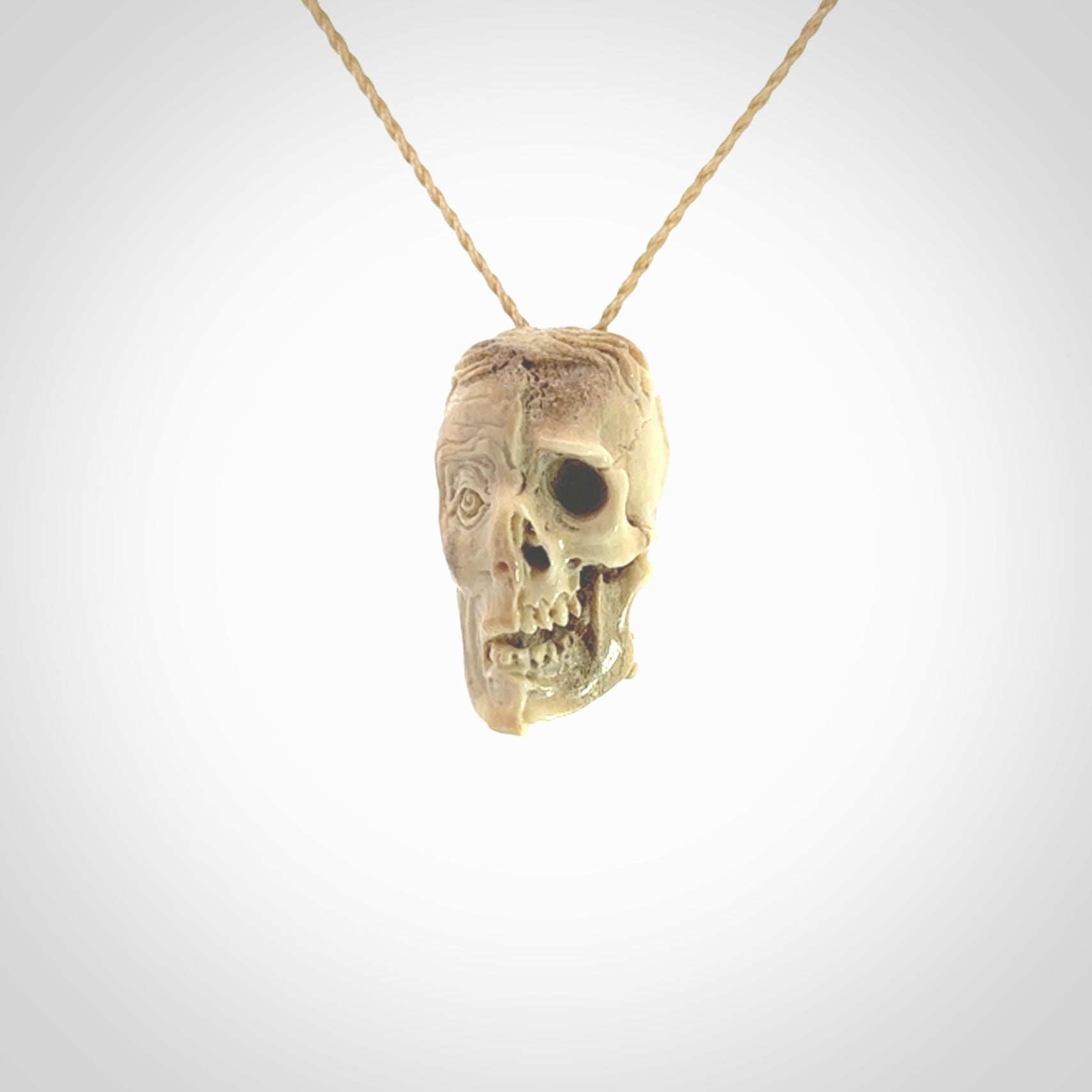 This photo shows a mummy skull pendant hand carved in deer antler. It is provided with a plaited cord necklace which is length adjustable.