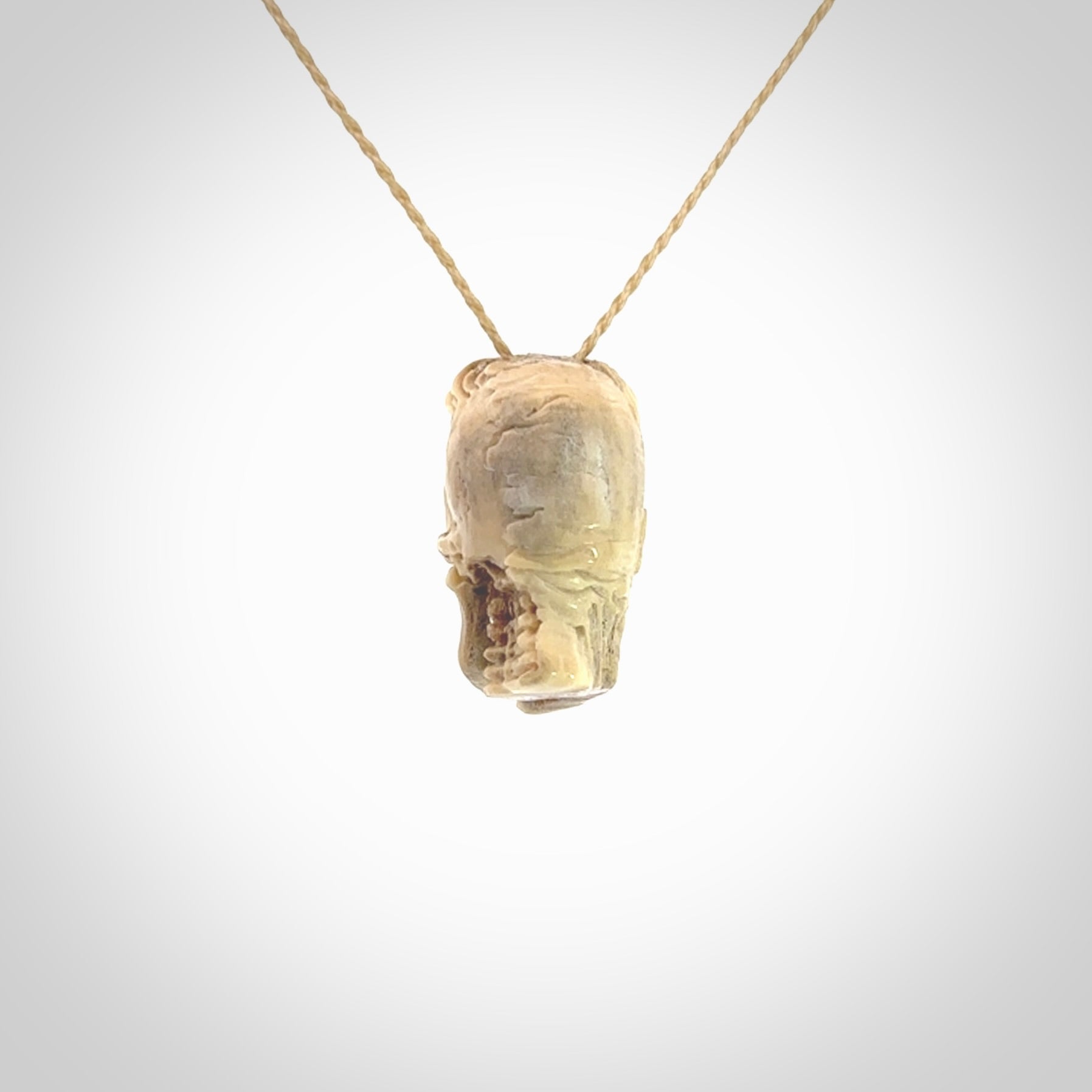 This photo shows a mummy skull pendant hand carved in deer antler. It is provided with a plaited cord necklace which is length adjustable.