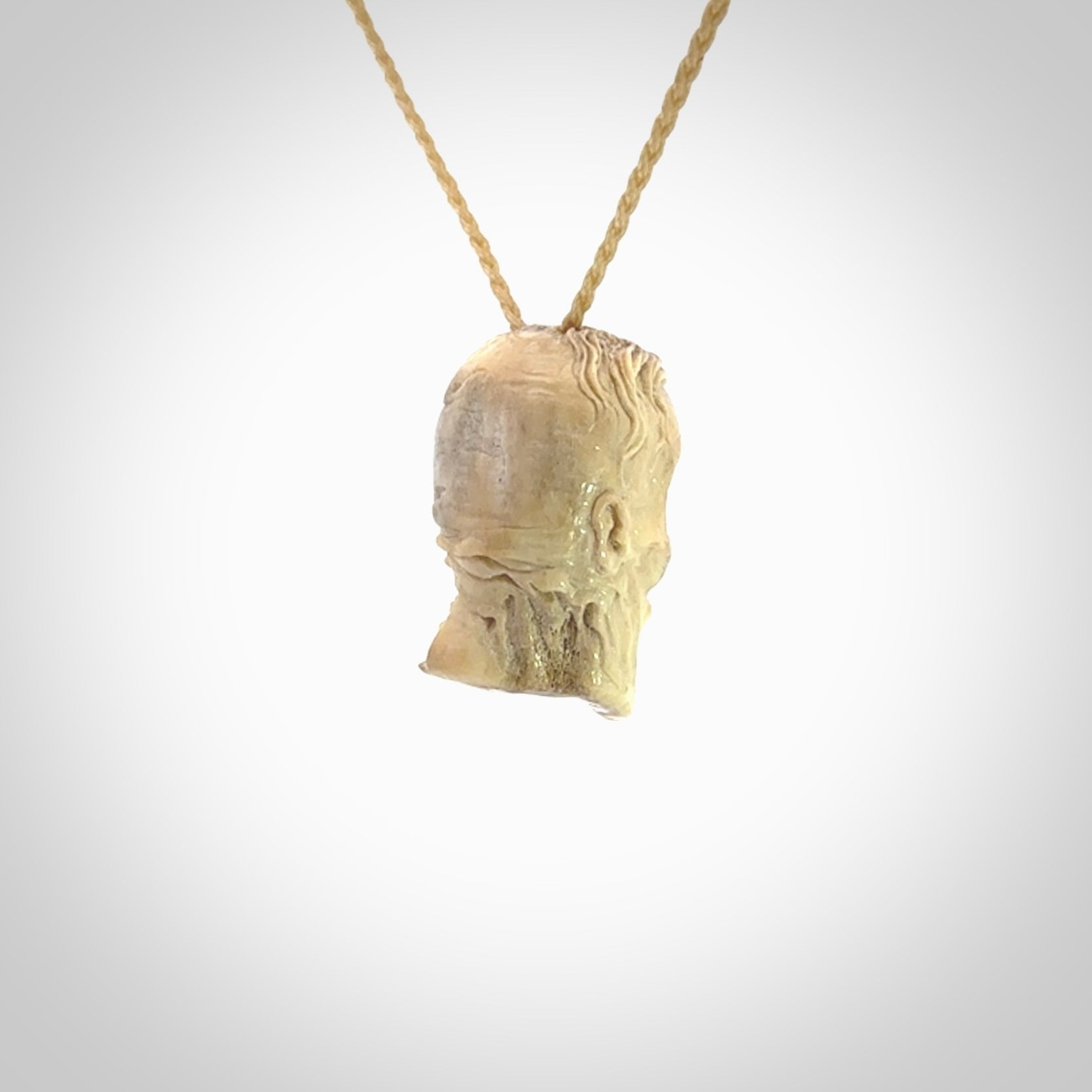 This photo shows a mummy skull pendant hand carved in deer antler. It is provided with a plaited cord necklace which is length adjustable.