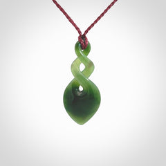 Hand carved New Zealand jade twist pendant. Carved in New Zealand by NZ Pacific. Unique double twist jewellery for sale online. Provided with an adjustable Burgundy cord.