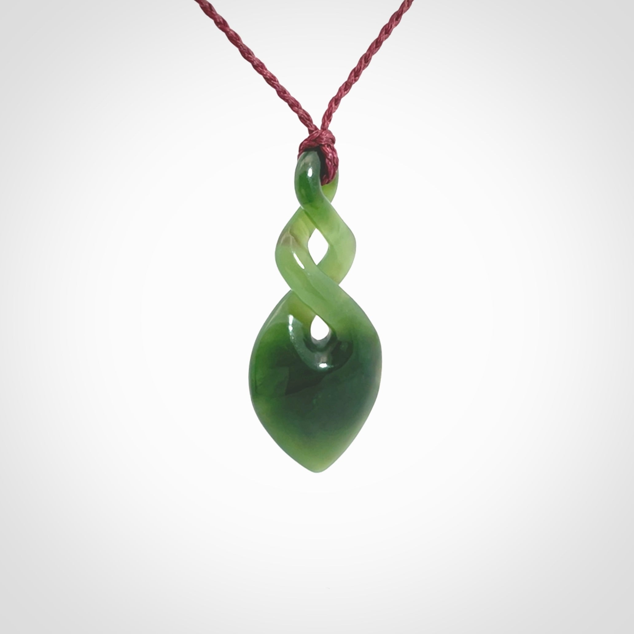 Hand carved New Zealand jade twist pendant. Carved in New Zealand by NZ Pacific. Unique double twist jewellery for sale online. Provided with an adjustable Burgundy cord.