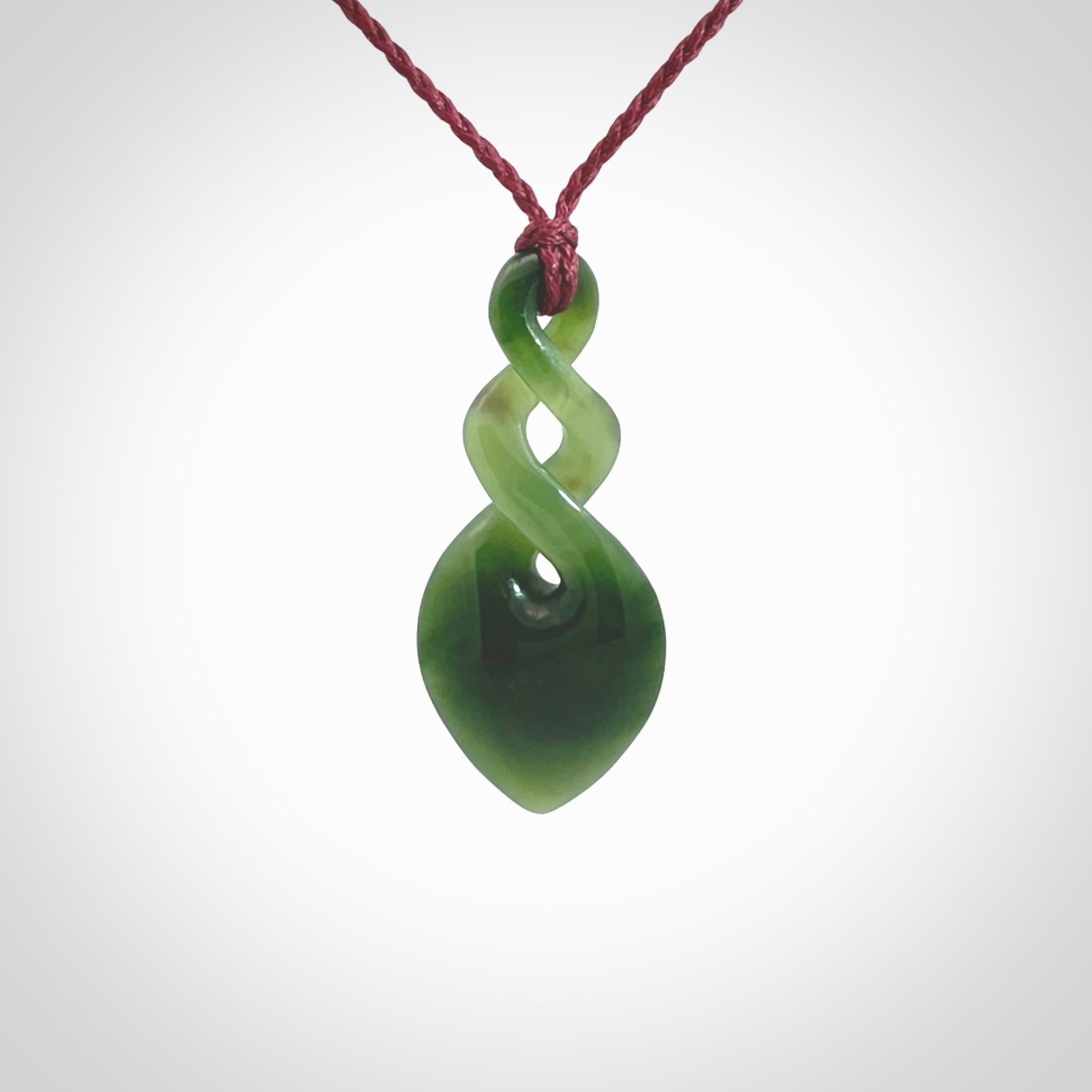 Hand carved New Zealand jade twist pendant. Carved in New Zealand by NZ Pacific. Unique double twist jewellery for sale online. Provided with an adjustable Burgundy cord.