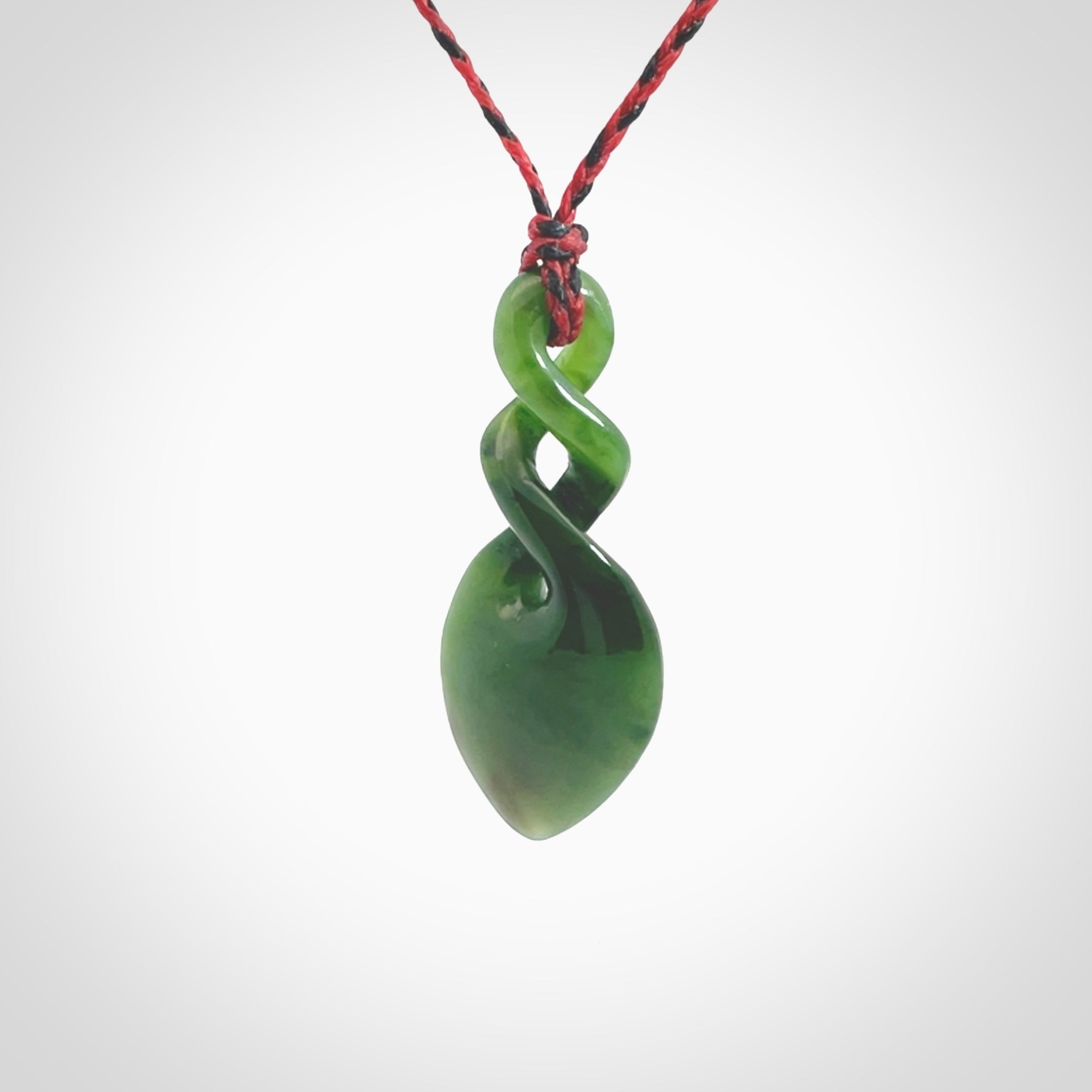 Hand carved New Zealand jade twist pendant. Carved in New Zealand by NZ Pacific. Unique double twist jewellery for sale online. Provided with an adjustable red/black cord.