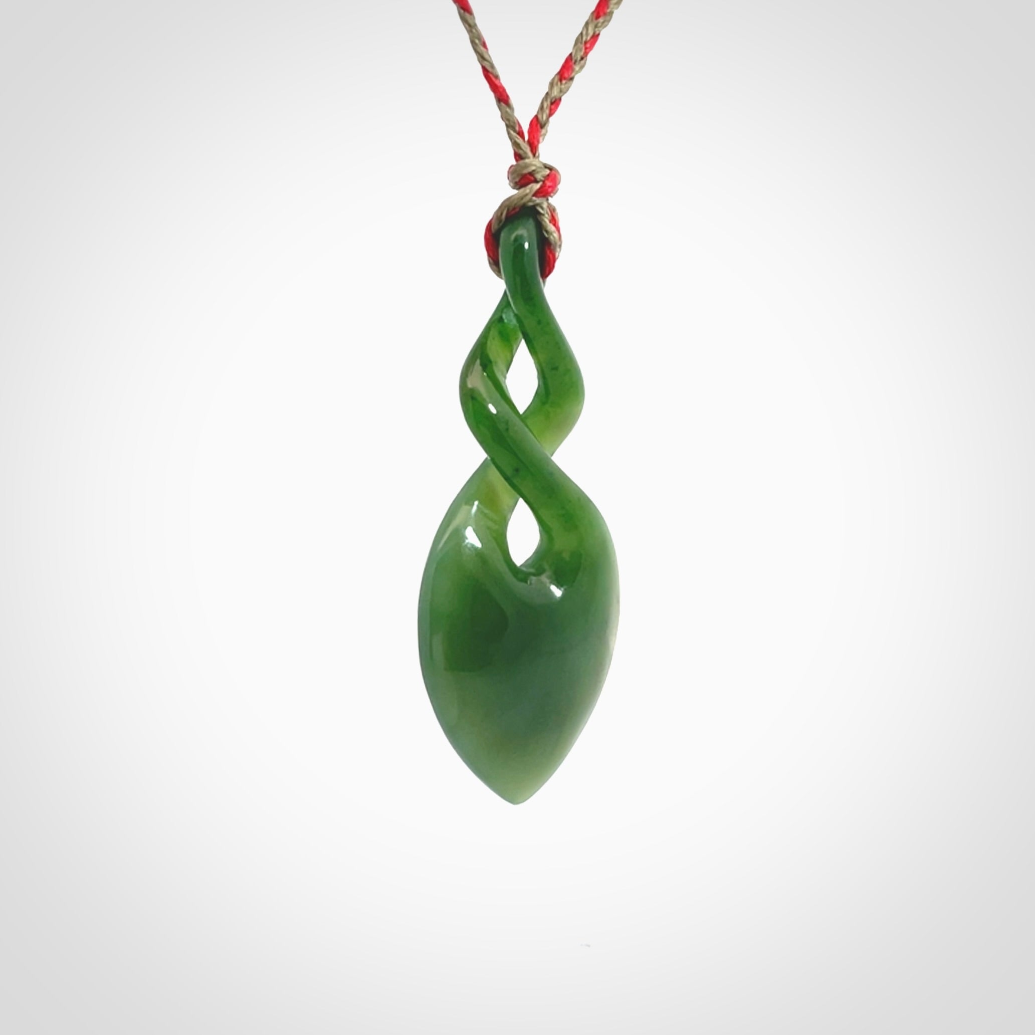 Hand carved New Zealand jade twist pendant. Carved in New Zealand by NZ Pacific. Unique double twist jewellery for sale online. Provided with an adjustable red/khaki cord.