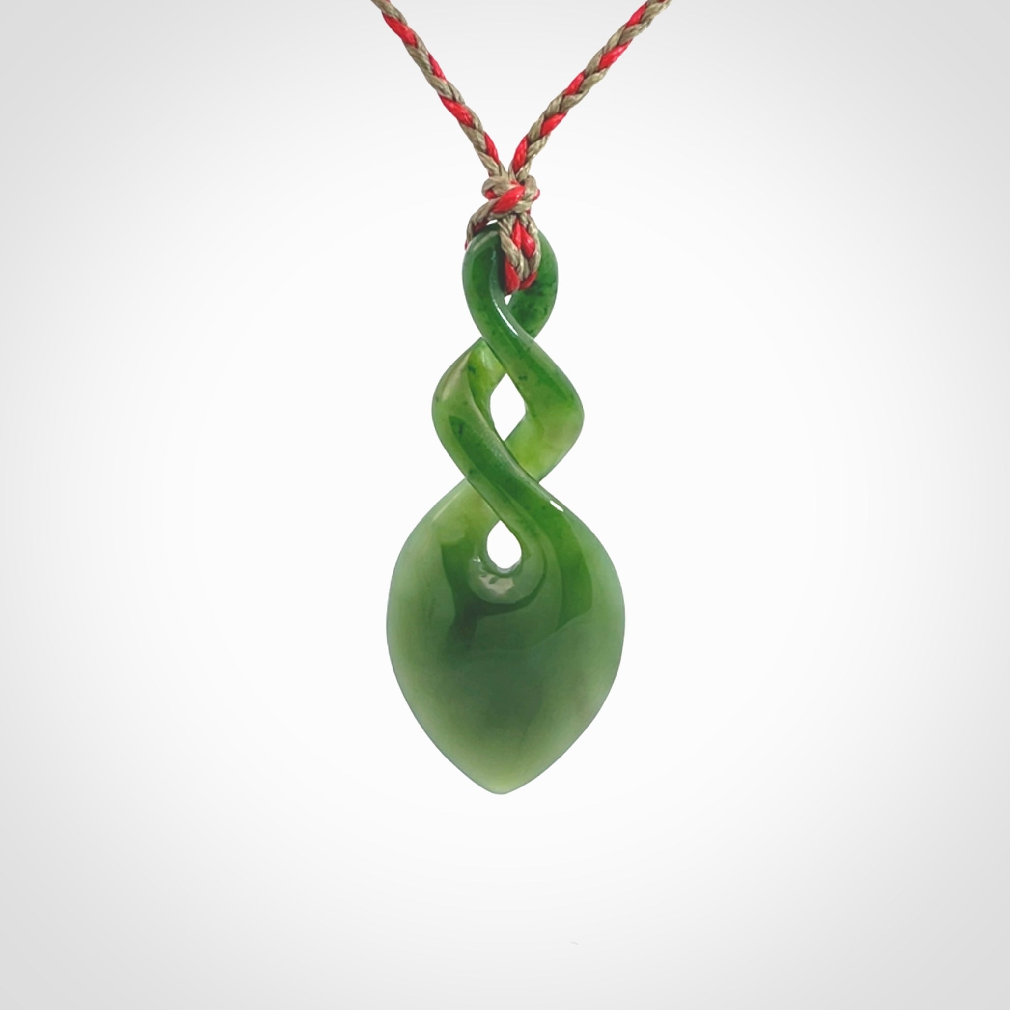 Hand carved New Zealand jade twist pendant. Carved in New Zealand by NZ Pacific. Unique double twist jewellery for sale online. Provided with an adjustable red/khaki cord.