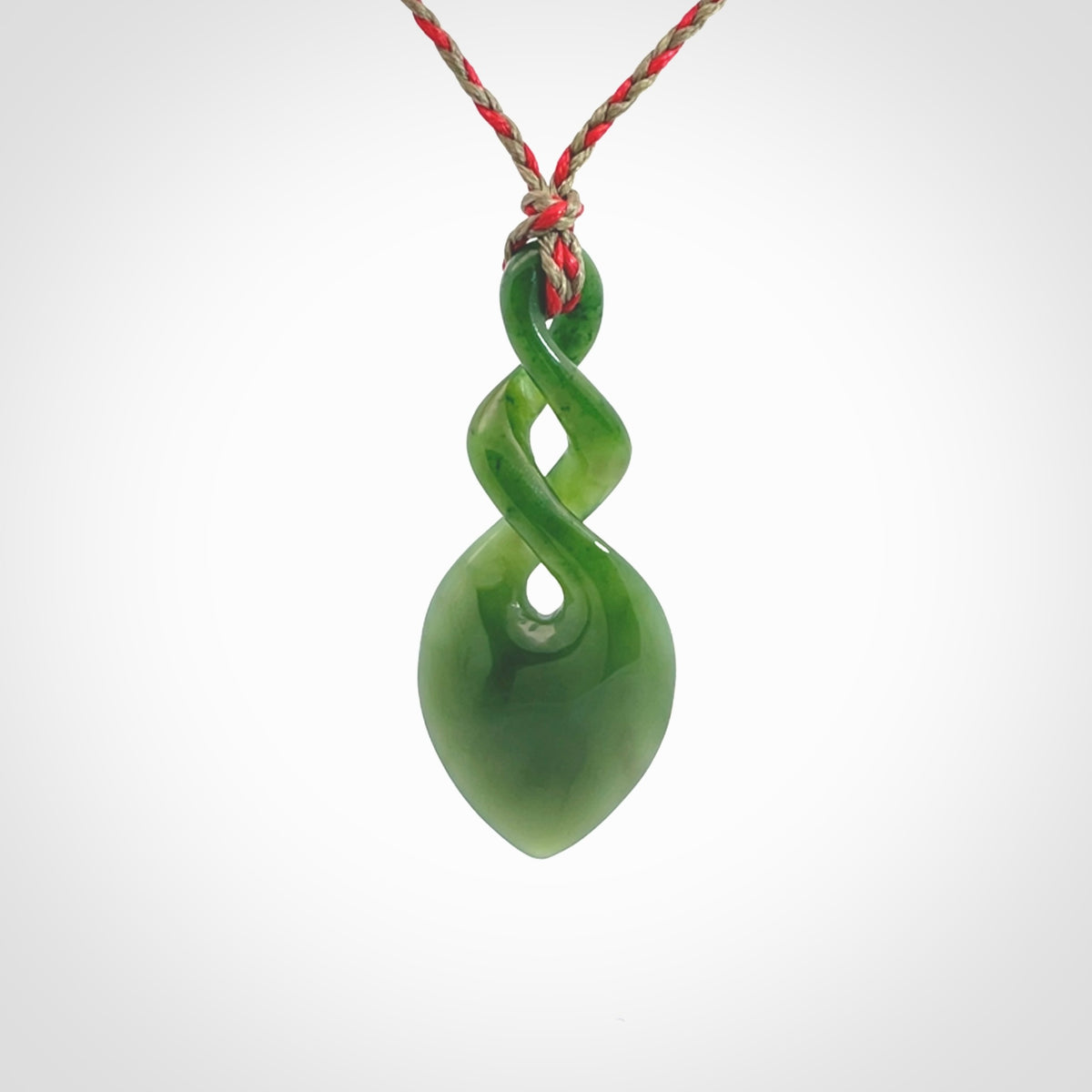 Hand carved New Zealand jade twist pendant. Carved in New Zealand by NZ Pacific. Unique double twist jewellery for sale online. Provided with an adjustable red/khaki cord.