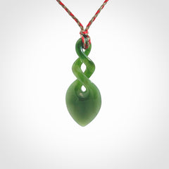 Hand carved New Zealand jade twist pendant. Carved in New Zealand by NZ Pacific. Unique double twist jewellery for sale online. Provided with an adjustable red/khaki cord.