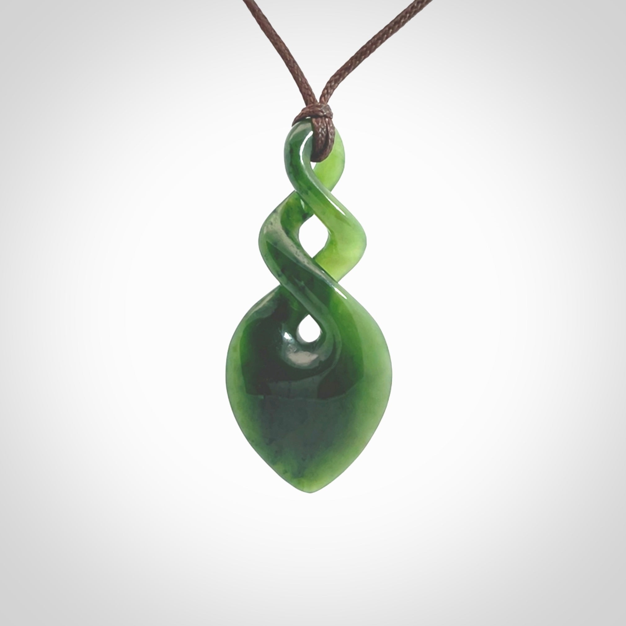 Hand carved New Zealand jade twist pendant. Carved in New Zealand by NZ Pacific. Unique double twist jewellery for sale online. Provided with an adjustable chocolate brown cord.