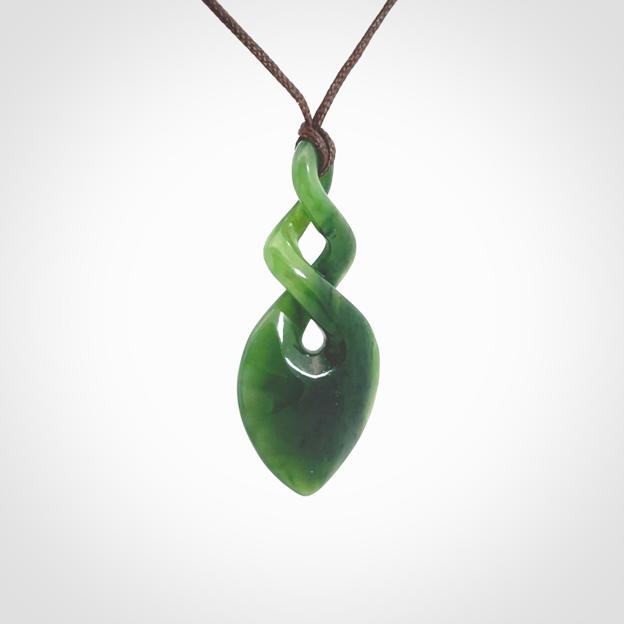 Hand carved New Zealand jade twist pendant. Carved in New Zealand by NZ Pacific. Unique double twist jewellery for sale online. Provided with an adjustable chocolate brown cord.