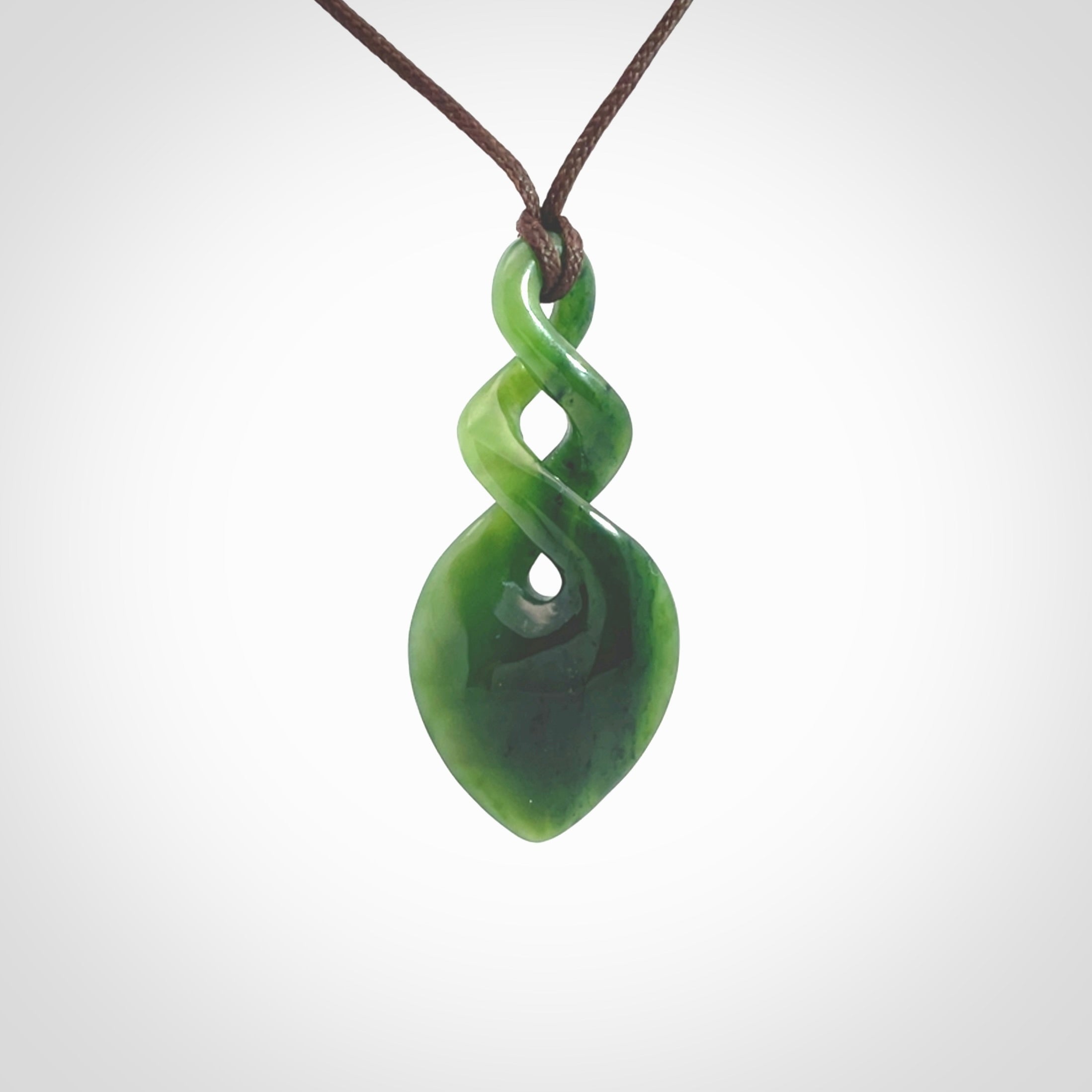 Hand carved New Zealand jade twist pendant. Carved in New Zealand by NZ Pacific. Unique double twist jewellery for sale online. Provided with an adjustable chocolate brown cord.