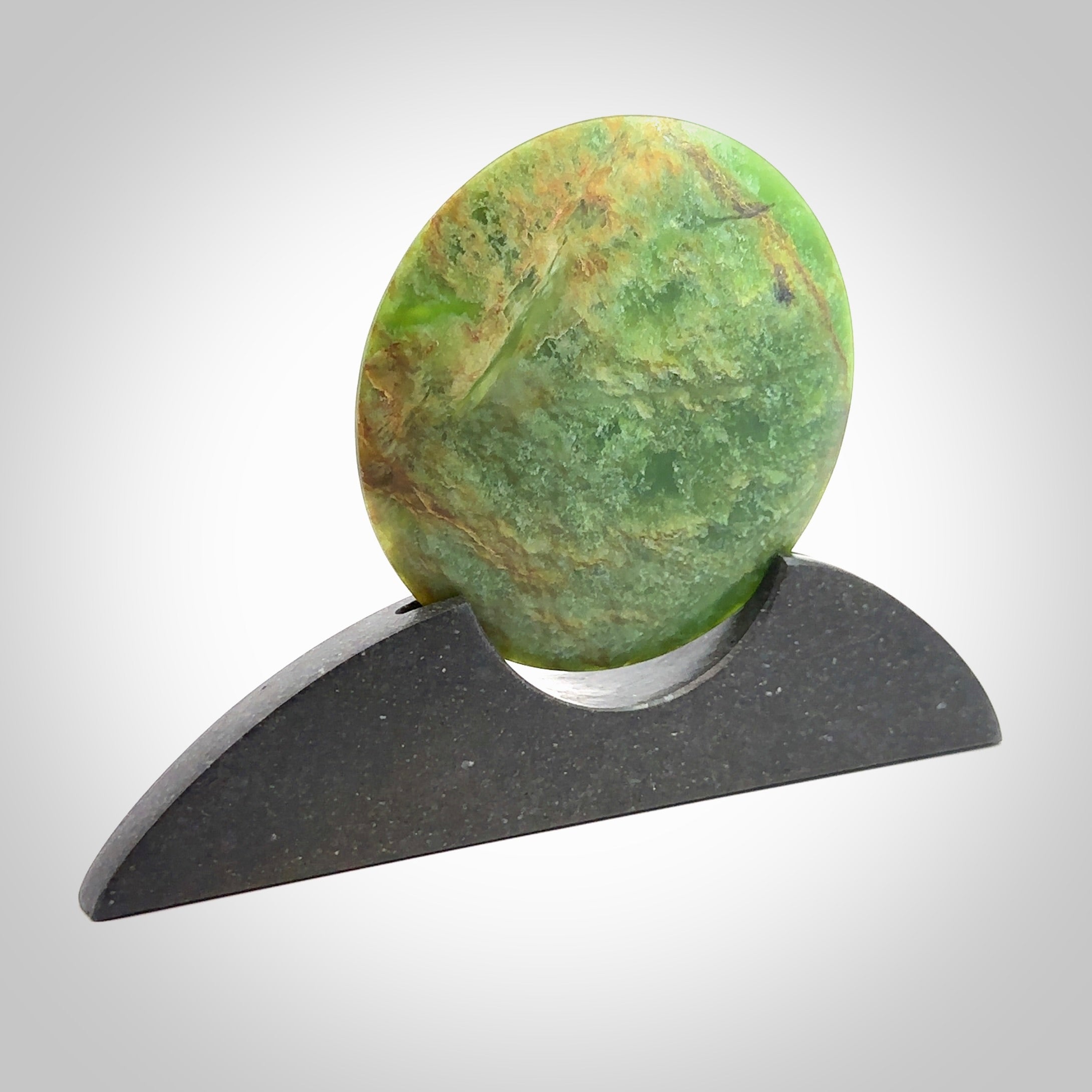 Hand carved New Zealand Flower Jade Disc with Greywacke stand sculpture. Hand carved here in New Zealand by Ric Moor. This is a 'one only' sculpture, a beautiful display piece. Small Jade disc sculpture for desk.