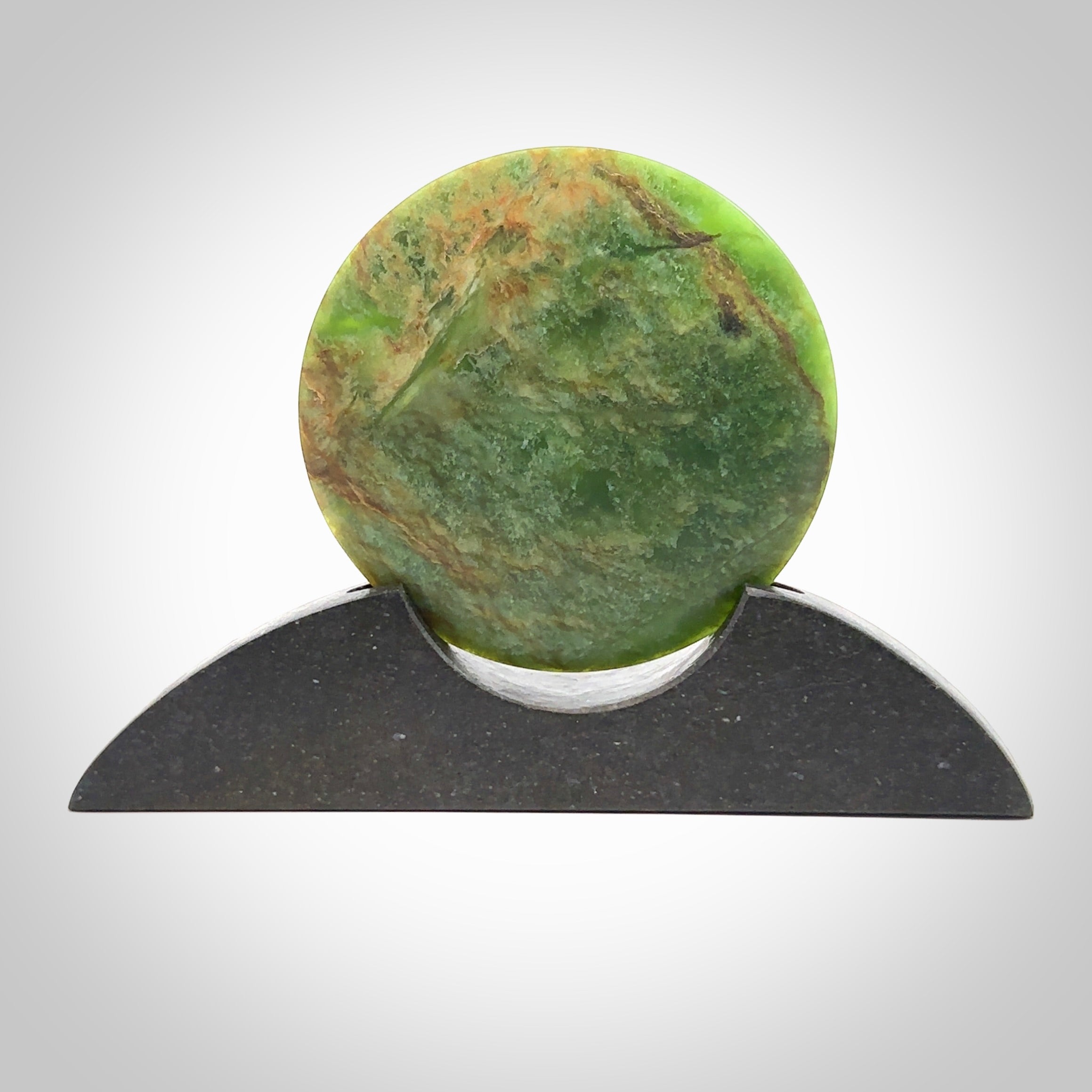 Hand carved New Zealand Flower Jade Disc with Greywacke stand sculpture. Hand carved here in New Zealand by Ric Moor. This is a 'one only' sculpture, a beautiful display piece. Small Jade disc sculpture for desk.