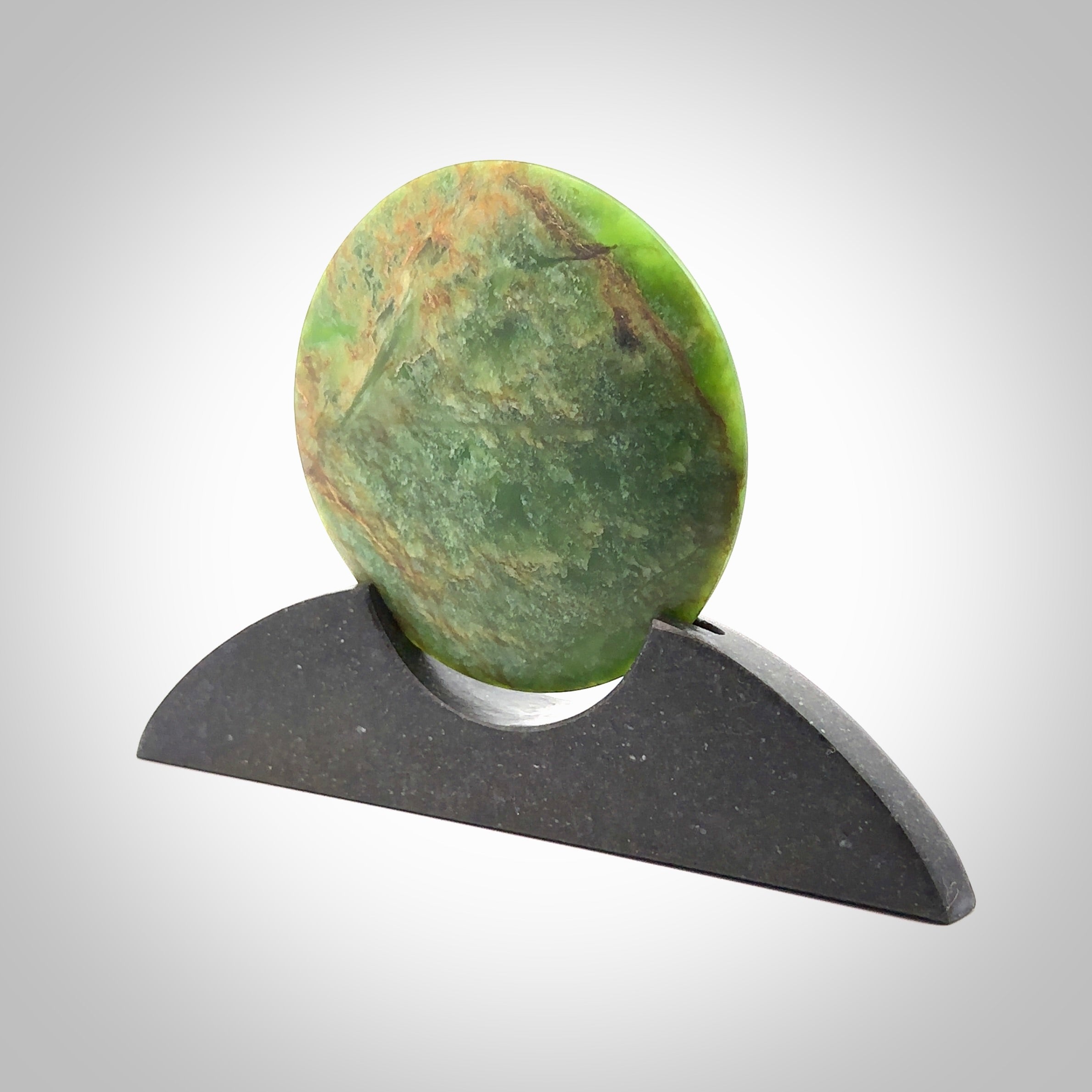 Hand carved New Zealand Flower Jade Disc with Greywacke stand sculpture. Hand carved here in New Zealand by Ric Moor. This is a 'one only' sculpture, a beautiful display piece. Small Jade disc sculpture for desk.