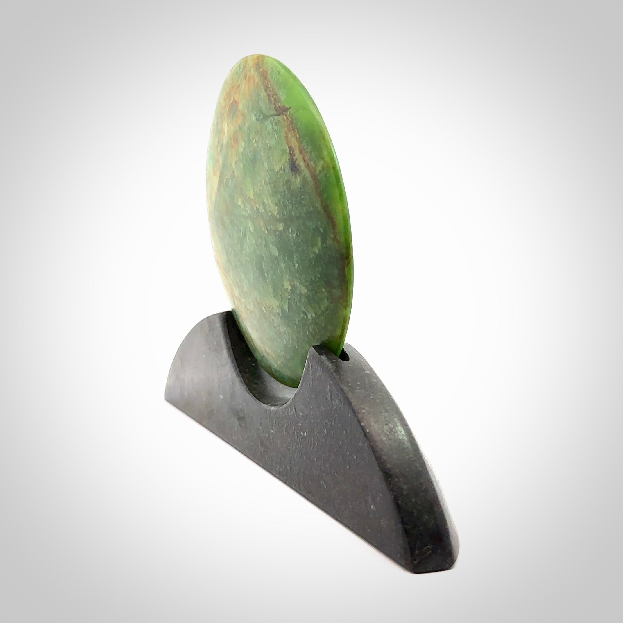 Hand carved New Zealand Flower Jade Disc with Greywacke stand sculpture. Hand carved here in New Zealand by Ric Moor. This is a 'one only' sculpture, a beautiful display piece. Small Jade disc sculpture for desk.