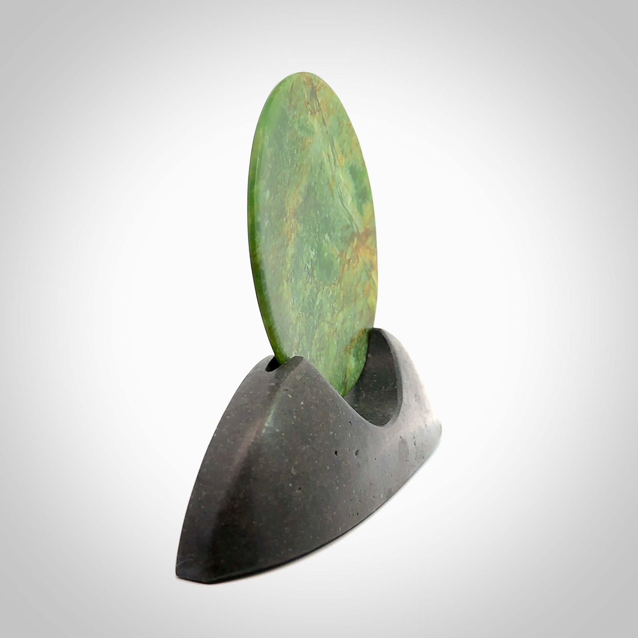 Hand carved New Zealand Flower Jade Disc with Greywacke stand sculpture. Hand carved here in New Zealand by Ric Moor. This is a 'one only' sculpture, a beautiful display piece. Small Jade disc sculpture for desk.