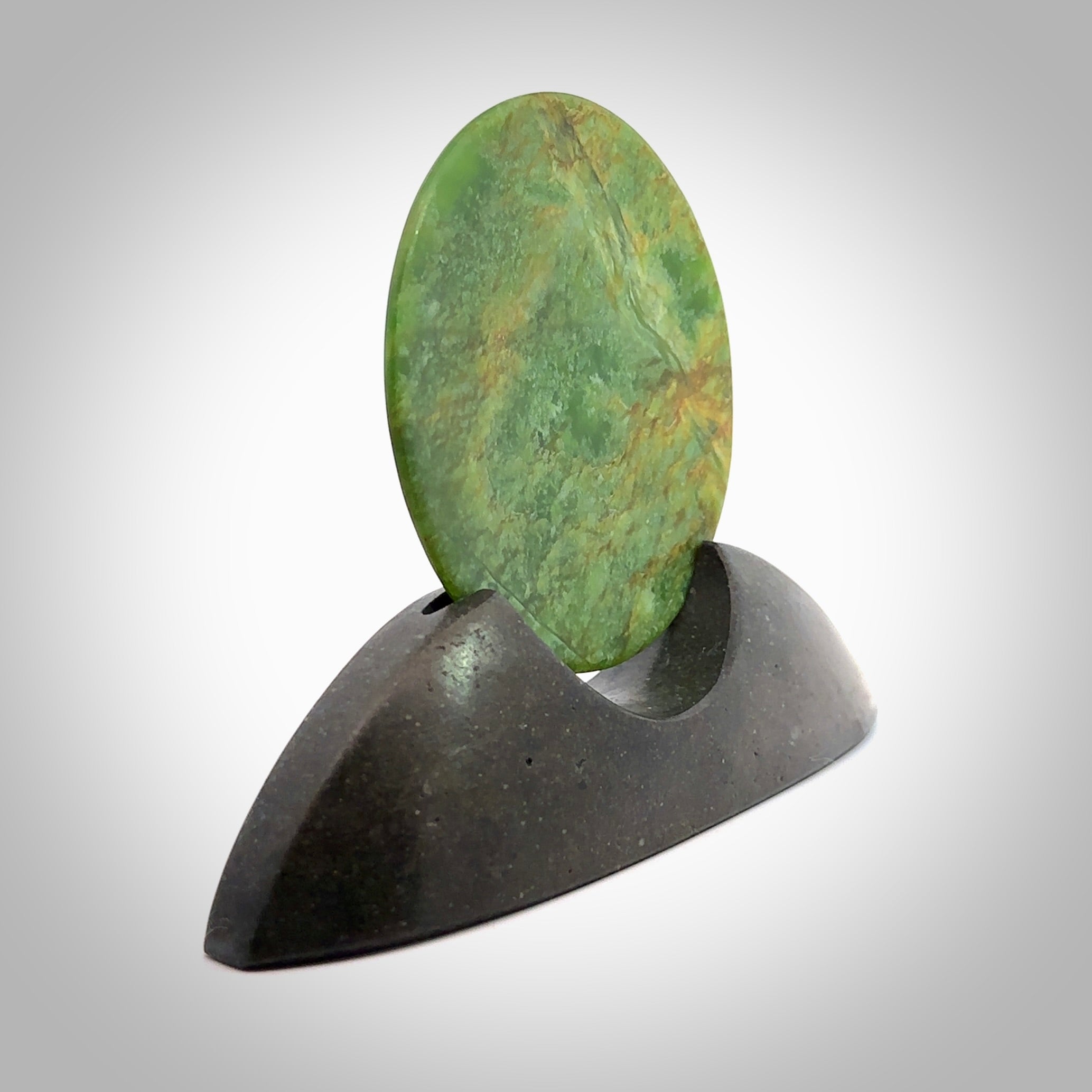 Hand carved New Zealand Flower Jade Disc with Greywacke stand sculpture. Hand carved here in New Zealand by Ric Moor. This is a 'one only' sculpture, a beautiful display piece. Small Jade disc sculpture for desk.