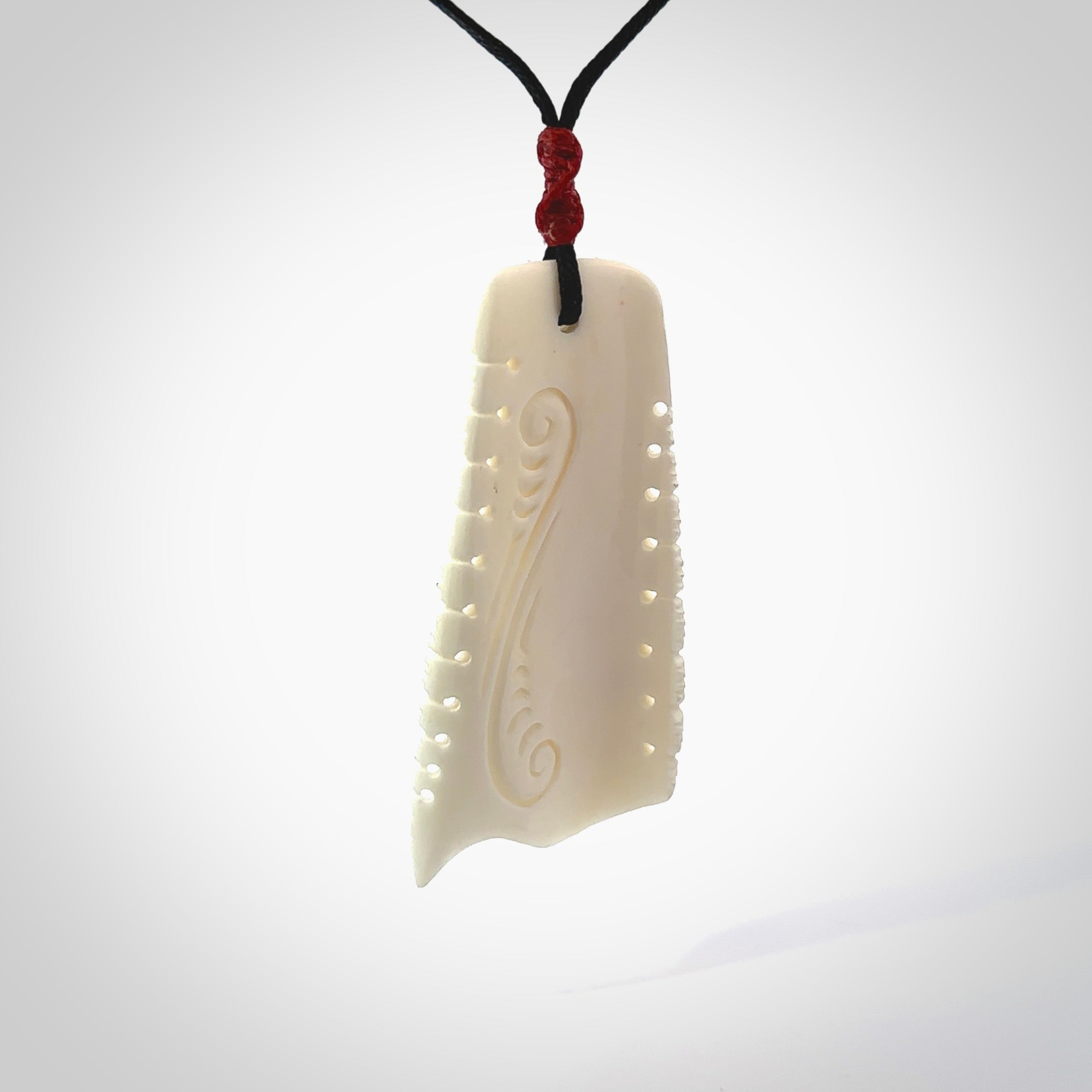 A hand carved contemporary bone toki pendant. The cord and binding is black and the cord is adjustable. Medium hand made etched toki with Koru engraving necklace. One off work of art to wear. Delivered in a woven kete pouch.