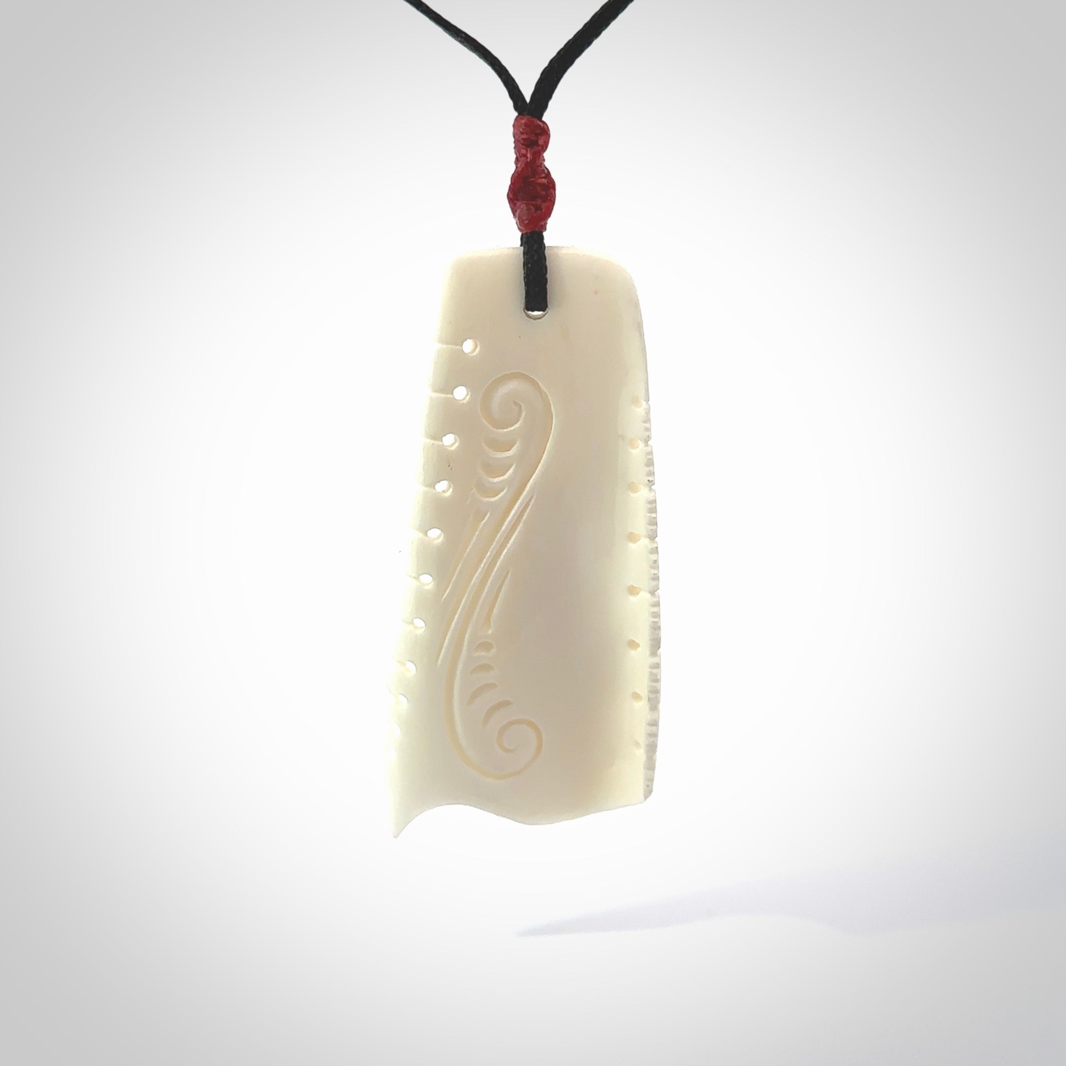 A hand carved contemporary bone toki pendant. The cord and binding is black and the cord is adjustable. Medium hand made etched toki with Koru engraving necklace. One off work of art to wear. Delivered in a woven kete pouch.