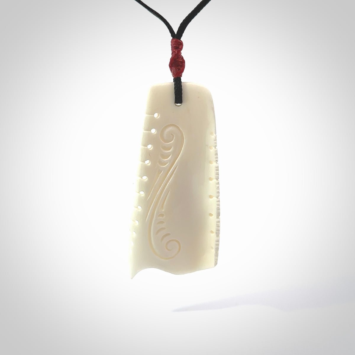 A hand carved contemporary bone toki pendant. The cord and binding is black and the cord is adjustable. Medium hand made etched toki with Koru engraving necklace. One off work of art to wear. Delivered in a woven kete pouch.