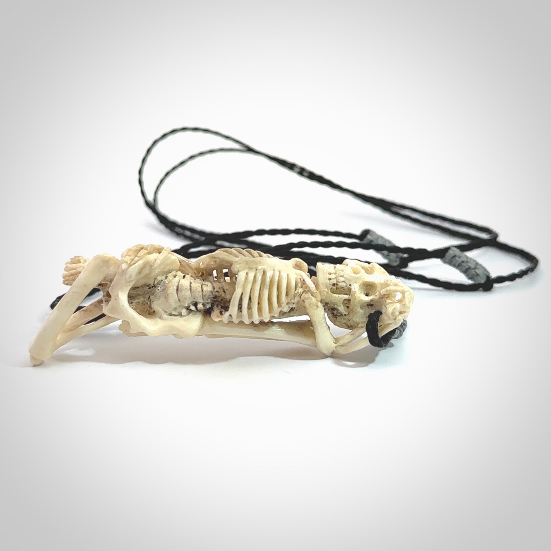 Hand carved deer antler, bone skeleton lying on its side pendant online for sale. Creative necklace for lovers of skeletons hand made from deer antler, bone. Free shipping worldwide. We provide this pendant with an adjustable cord.