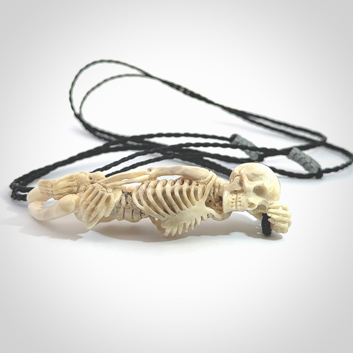 Hand carved deer antler, bone skeleton lying on its side pendant online for sale. Creative necklace for lovers of skeletons hand made from deer antler, bone. Free shipping worldwide. We provide this pendant with an adjustable cord.