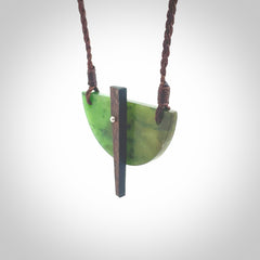 This piece is a contemporary shield pendant carved from jade from New Zealand. It is a deep green colour. The cord is brown and is length adjustable. Hand made with Australian Black Jade and Jade.