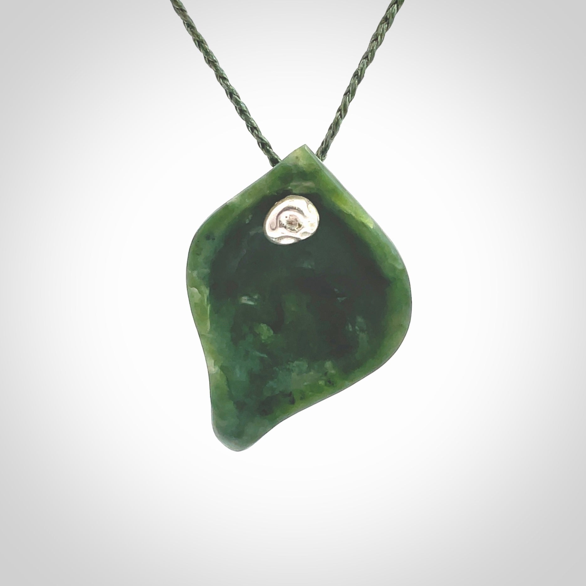 This picture shows a hand carved drop pendant made from a deep green coloured New Zealand Pounamu, jade. The front face is a concave, cupped design and the back is round. It is provided with an adjustable fern green cord in a woven kete pouch. Shipped to you with Express Courier.