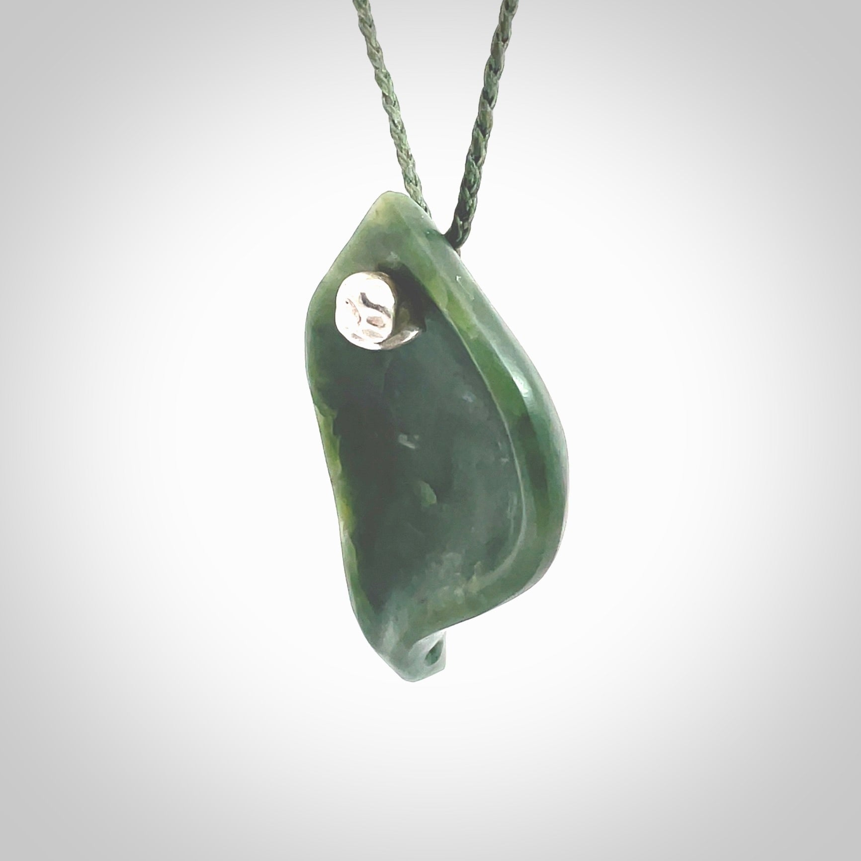 This picture shows a hand carved drop pendant made from a deep green coloured New Zealand Pounamu, jade. The front face is a concave, cupped design and the back is round. It is provided with an adjustable fern green cord in a woven kete pouch. Shipped to you with Express Courier.