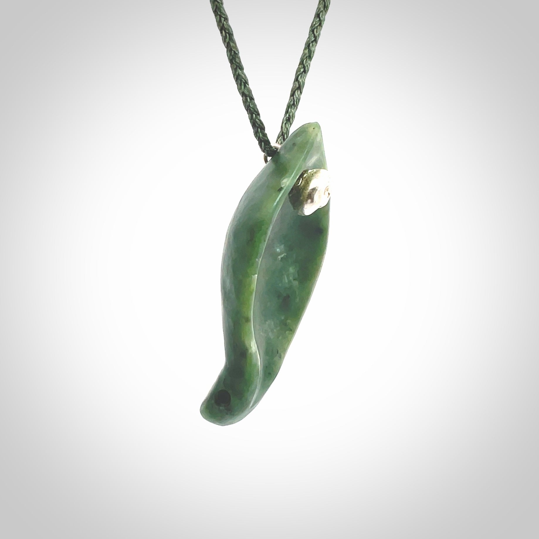 This picture shows a hand carved drop pendant made from a deep green coloured New Zealand Pounamu, jade. The front face is a concave, cupped design and the back is round. It is provided with an adjustable fern green cord in a woven kete pouch. Shipped to you with Express Courier.