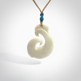 Hand carved bone hook pendant hand made by Peter Mitchell in New Zealand. This bone hook is provided with an adjustable tan cord and packaged in a woven kete pouch. Free delivery worldwide.