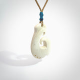 Hand carved bone hook pendant hand made by Peter Mitchell in New Zealand. This bone hook is provided with an adjustable tan cord and packaged in a woven kete pouch. Free delivery worldwide.