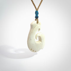 Hand carved bone hook pendant hand made by Peter Mitchell in New Zealand. This bone hook is provided with an adjustable tan cord and packaged in a woven kete pouch. Free delivery worldwide.