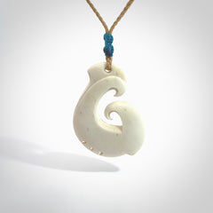 Hand carved bone hook pendant hand made by Peter Mitchell in New Zealand. This bone hook is provided with an adjustable tan cord and packaged in a woven kete pouch. Free delivery worldwide.