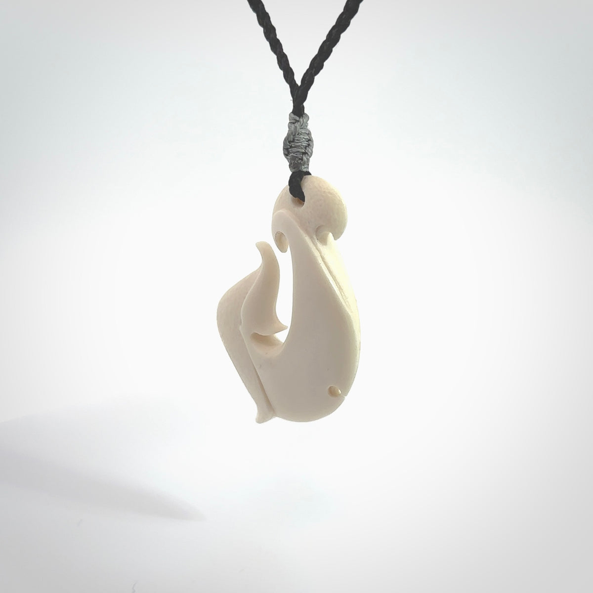 Hand carved bone hook pendant hand made by Peter Mitchell in New Zealand. This bone hook is provided with an adjustable black cord and packaged in a woven kete pouch. Free delivery worldwide.