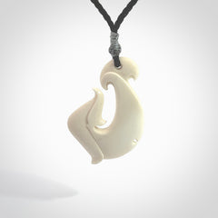 Hand carved bone hook pendant hand made by Peter Mitchell in New Zealand. This bone hook is provided with an adjustable black cord and packaged in a woven kete pouch. Free delivery worldwide.