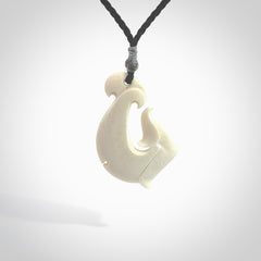 Hand carved bone hook pendant hand made by Peter Mitchell in New Zealand. This bone hook is provided with an adjustable black cord and packaged in a woven kete pouch. Free delivery worldwide.