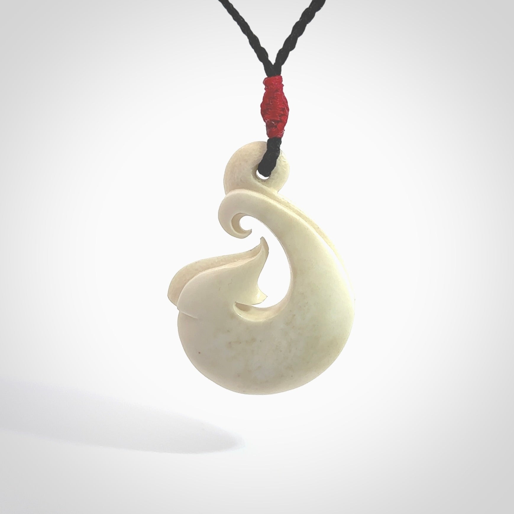 Hand carved bone hook pendant hand made by Peter Mitchell in New Zealand. This bone hook is provided with an adjustable black cord and packaged in a woven kete pouch. Free delivery worldwide.