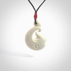 Hand carved bone hook pendant hand made by Peter Mitchell in New Zealand. This bone hook is provided with an adjustable black cord and packaged in a woven kete pouch. Free delivery worldwide.