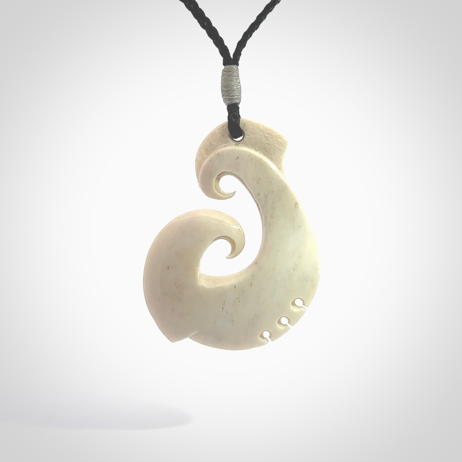 Hand carved bone hook pendant hand made by Peter Mitchell in New Zealand. This bone hook is provided with an adjustable black cord and packaged in a woven kete pouch. Free delivery worldwide.